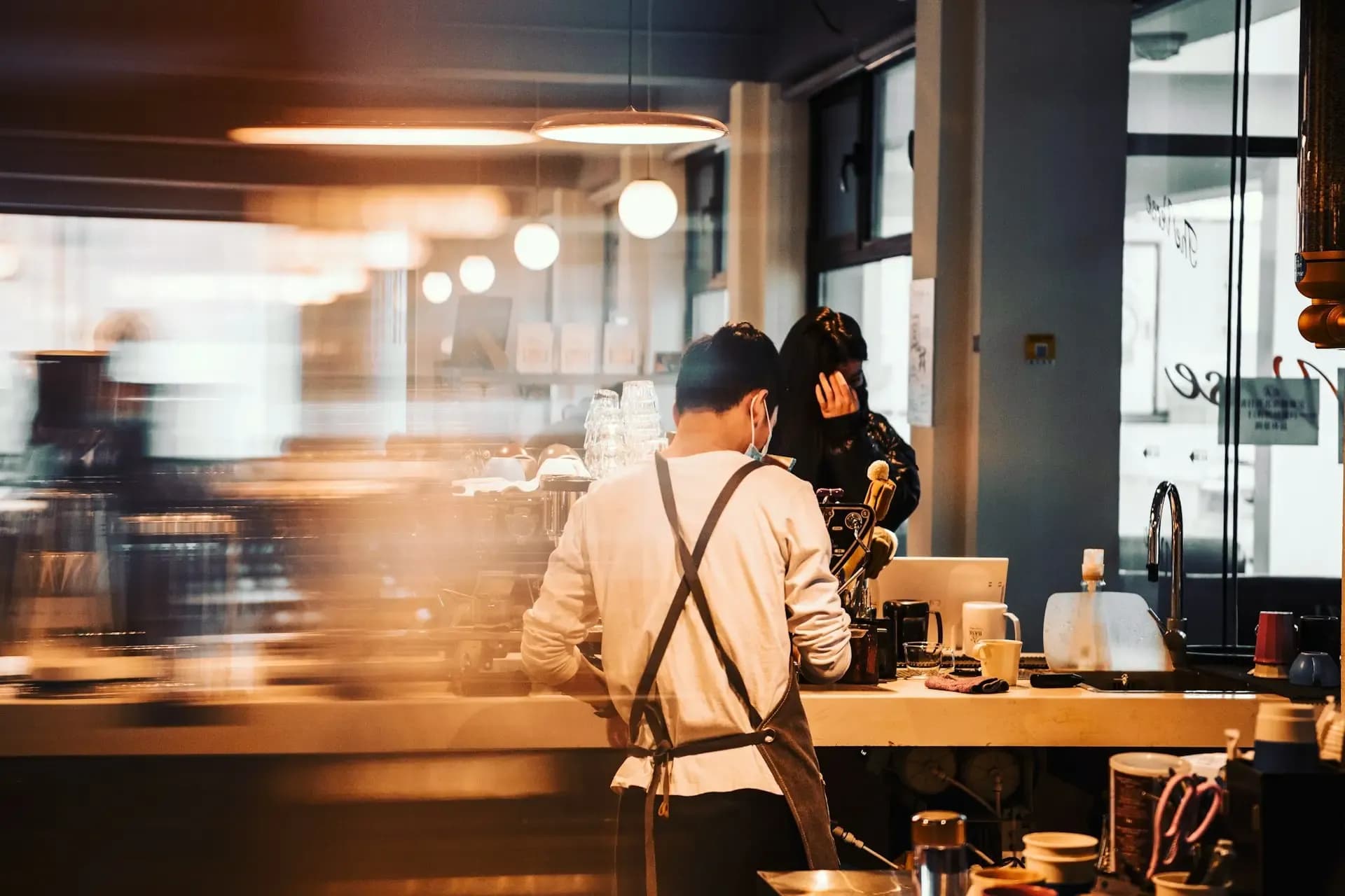 Nhân viên pha chế làm việc tại quầy của một cửa hàng cà phê