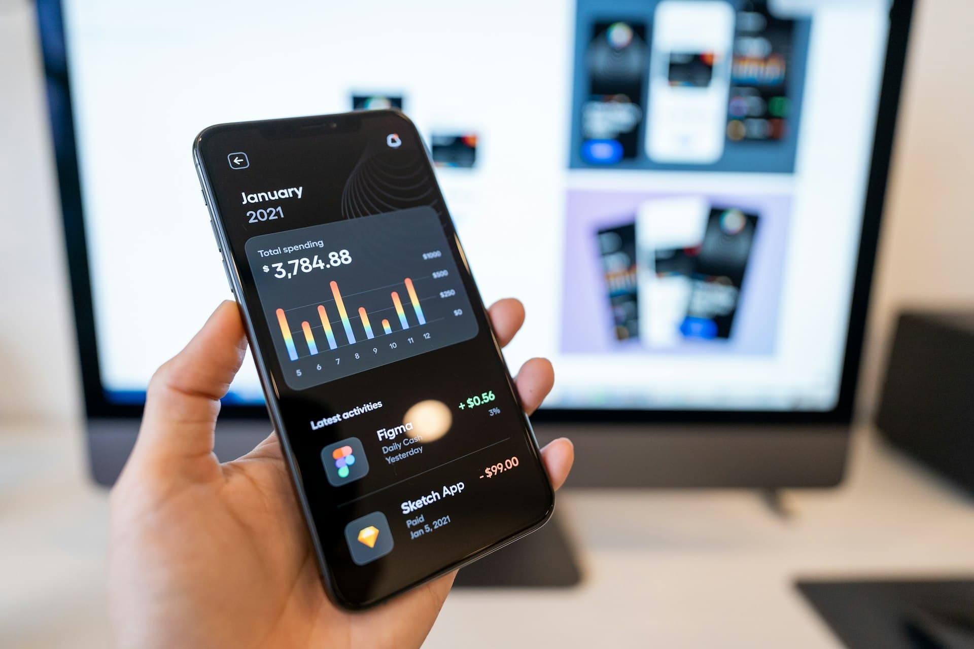Điện thoại hiển thị giao diện ứng dụng mobile với biểu đồ số liệu